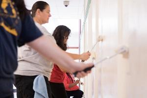 Dollars for Doers Tile Baxter employees painting a wall